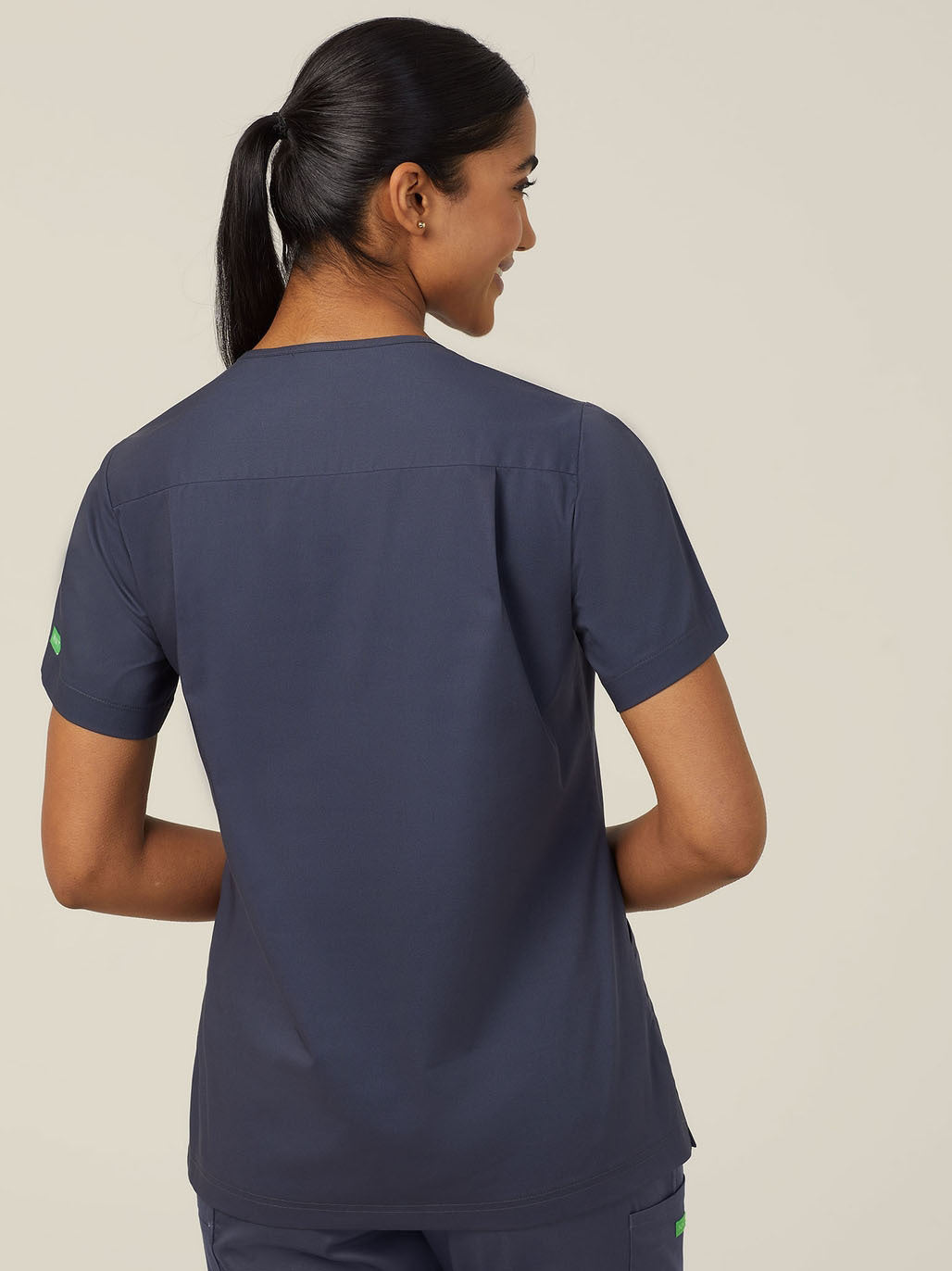 Woman wearing navy blue scrubs, back view.