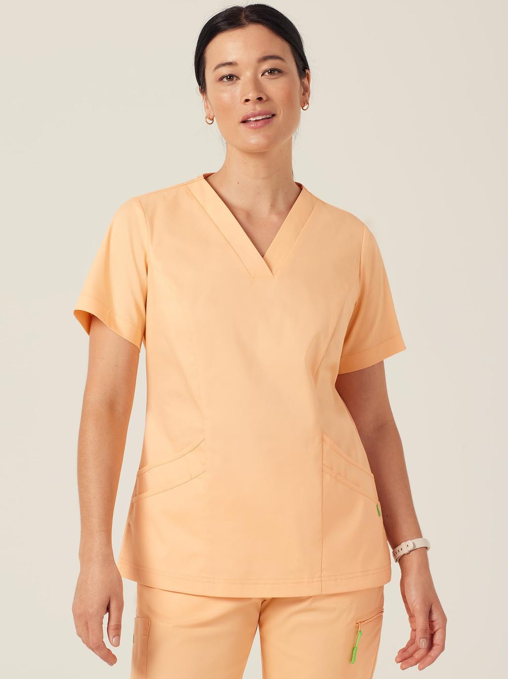 A woman wearing peach scrubs.