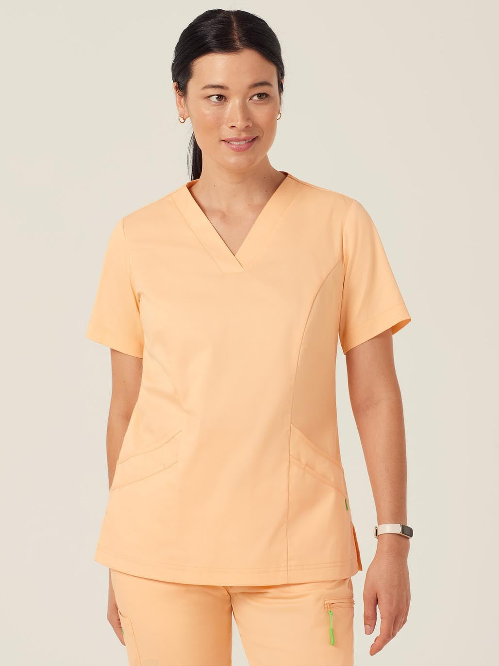 A woman wearing peach-colored scrubs.